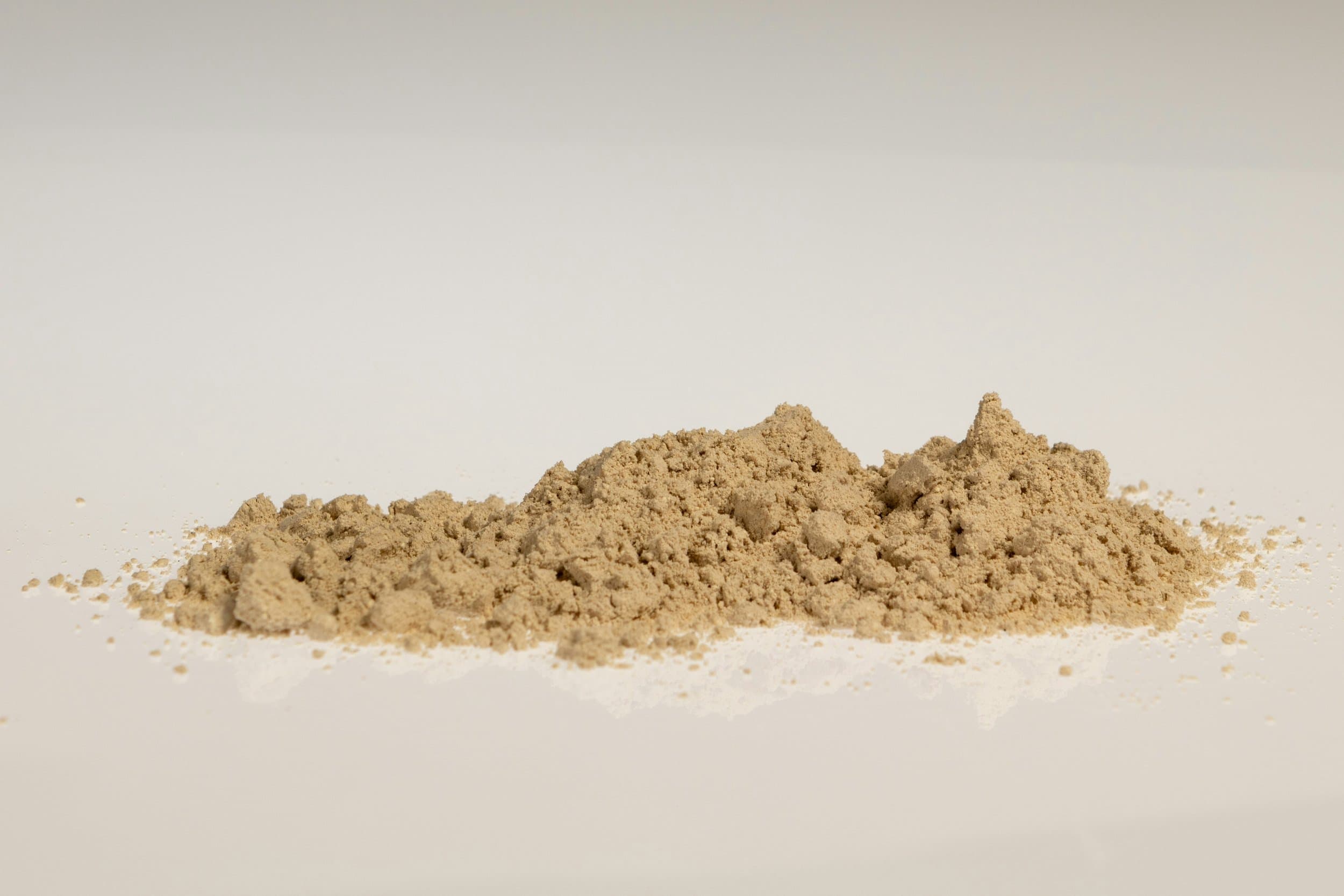 A pile of protein powder on a light surface.